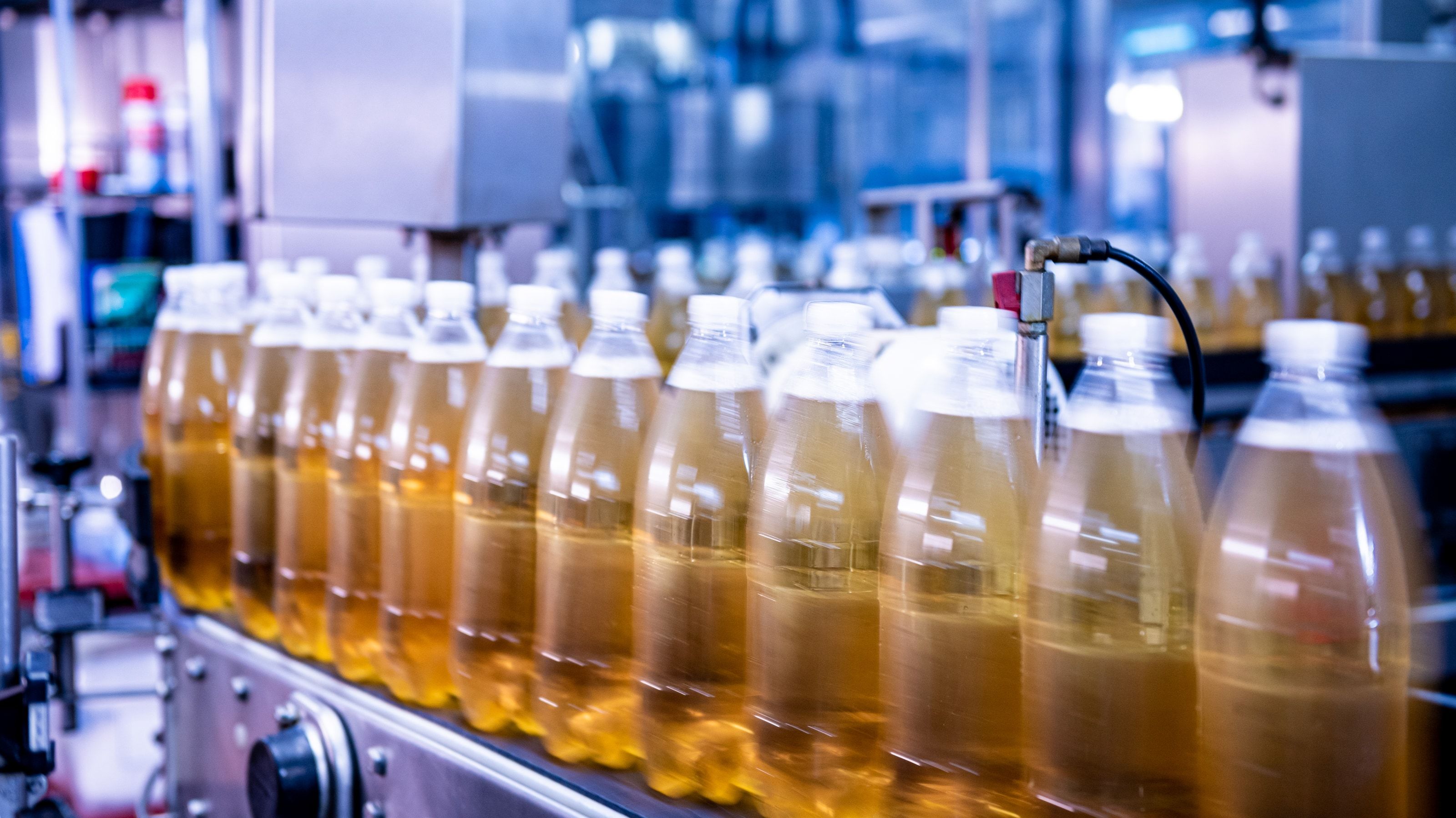 Línea de envasado de bebidas con cintas transportadoras de botellas y equipos de proceso