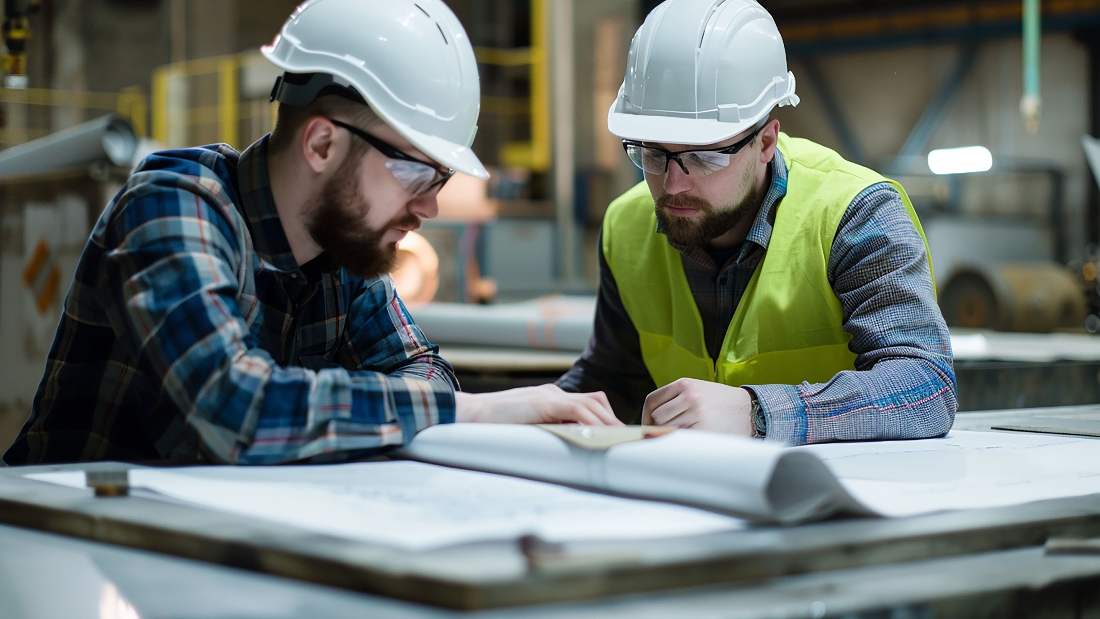 Responsable e ingeniero revisando planos técnicos en una planta industrial